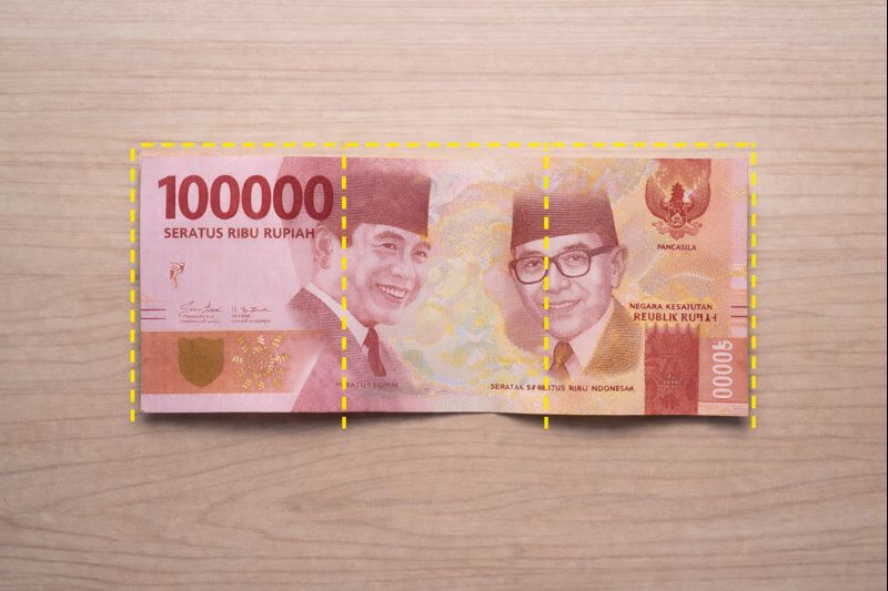 Ilustrasi pelipatan uang menjadi 3 bagian untuk membantu penilaian keutuhan minimal 2/3 sesuai ketentuan